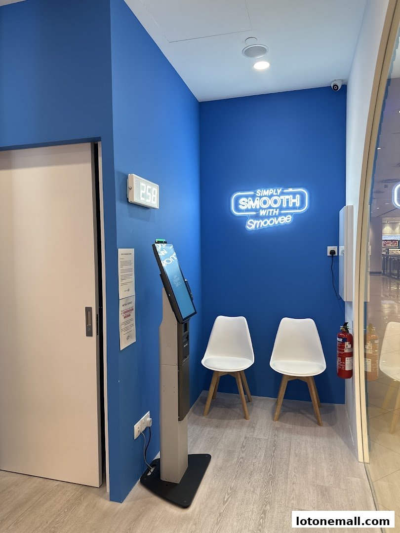 A waiting area with two chairs, a digital display, and a neon sign for Smoovee Skin.