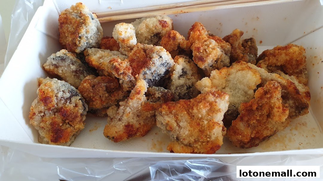 A close-up view of a white paper container filled with crispy, golden-brown fried snacks.