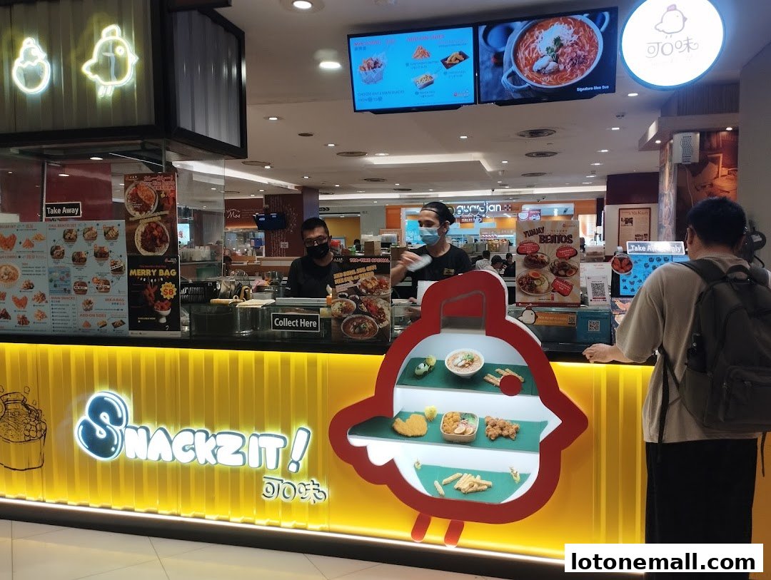 A food stall with a bright yellow counter displaying various snacks and menu items.