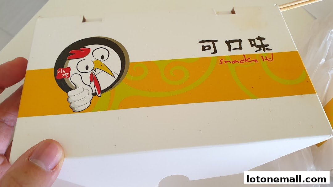 A person holds a white snack box with a cartoon chicken logo and Chinese text.