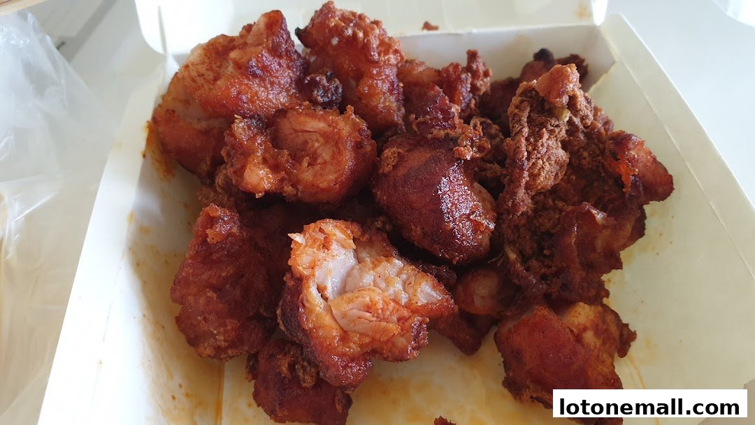 A close-up shot of crispy, golden-brown fried chicken pieces in a white takeaway box.