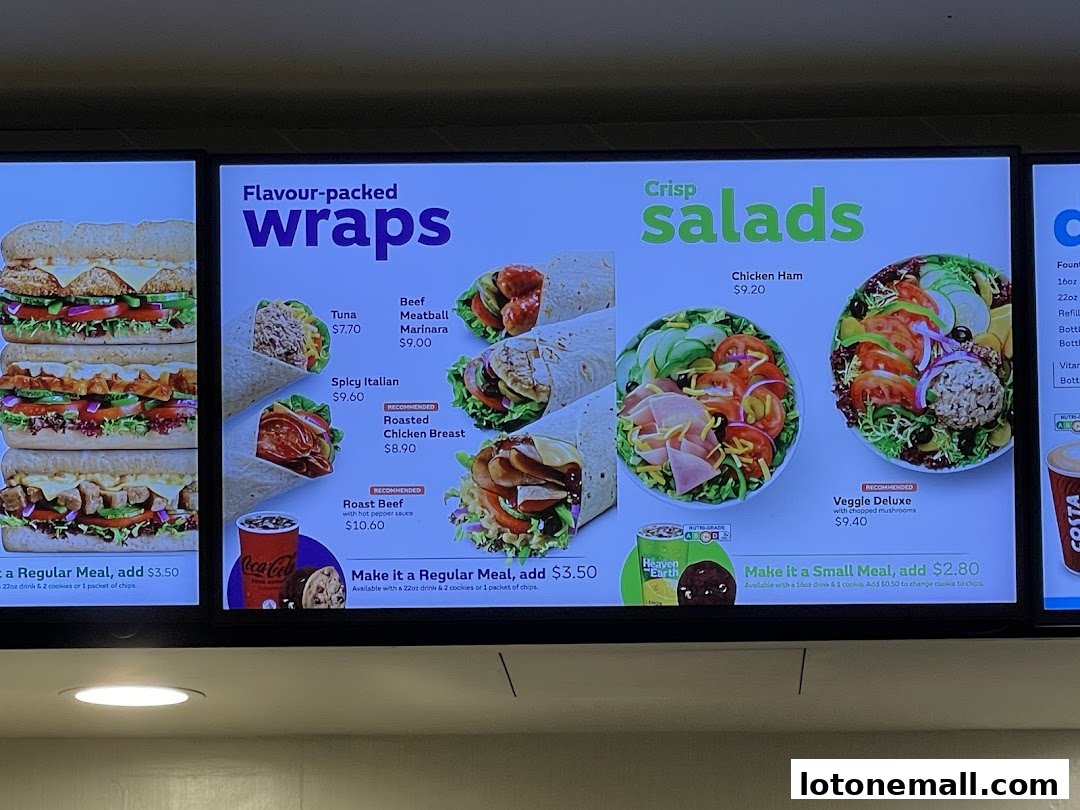 A digital menu board displaying wraps and salads with prices and images.