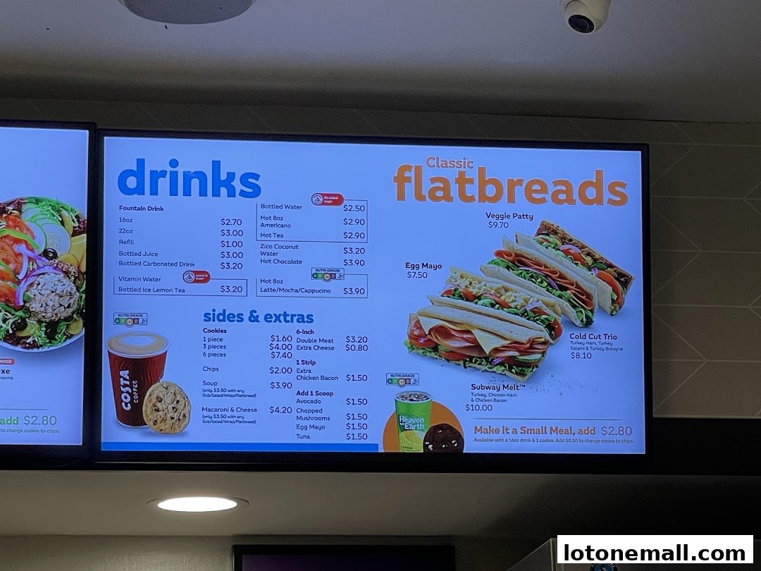 A digital menu board displaying drinks, flatbreads, and sides with prices.