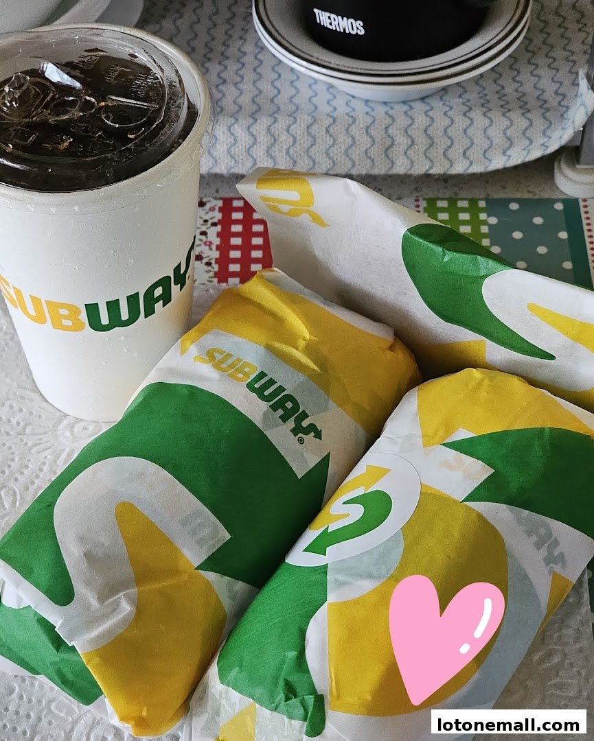 Subway sandwiches and a drink are neatly arranged on a table, ready to be enjoyed.