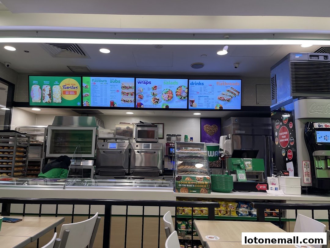 A Subway restaurant counter with digital menus displaying food and drink options.
