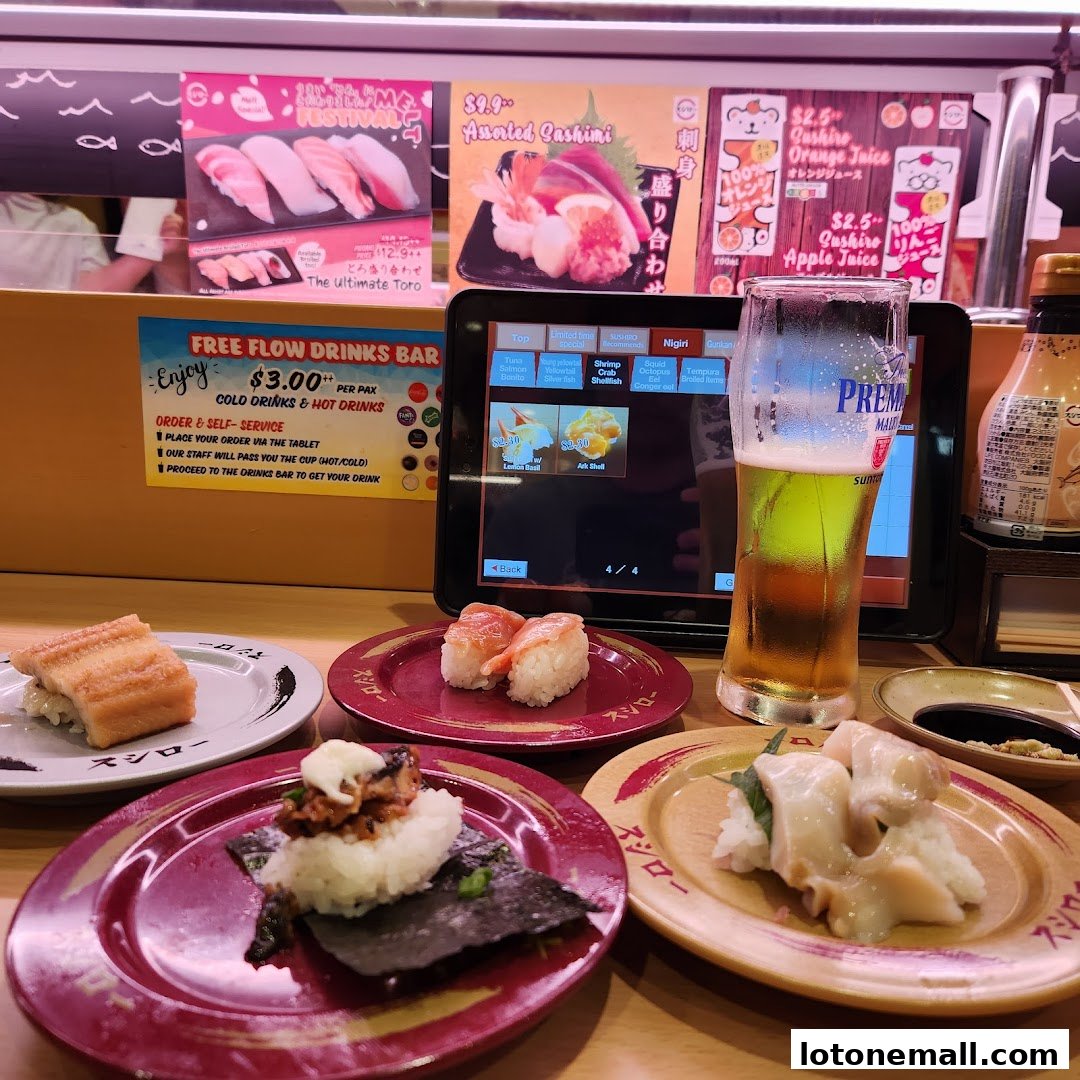 A table at Sushiro Lot One with various sushi dishes, a beer, and a tablet ordering system.