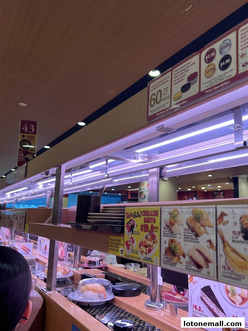 A conveyor belt sushi restaurant with various sushi dishes and desserts on display.