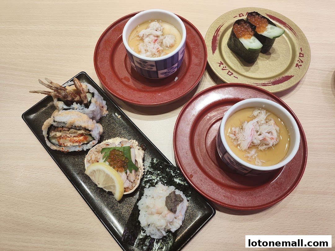 A variety of sushi dishes and chawanmushi are arranged on a wooden table.