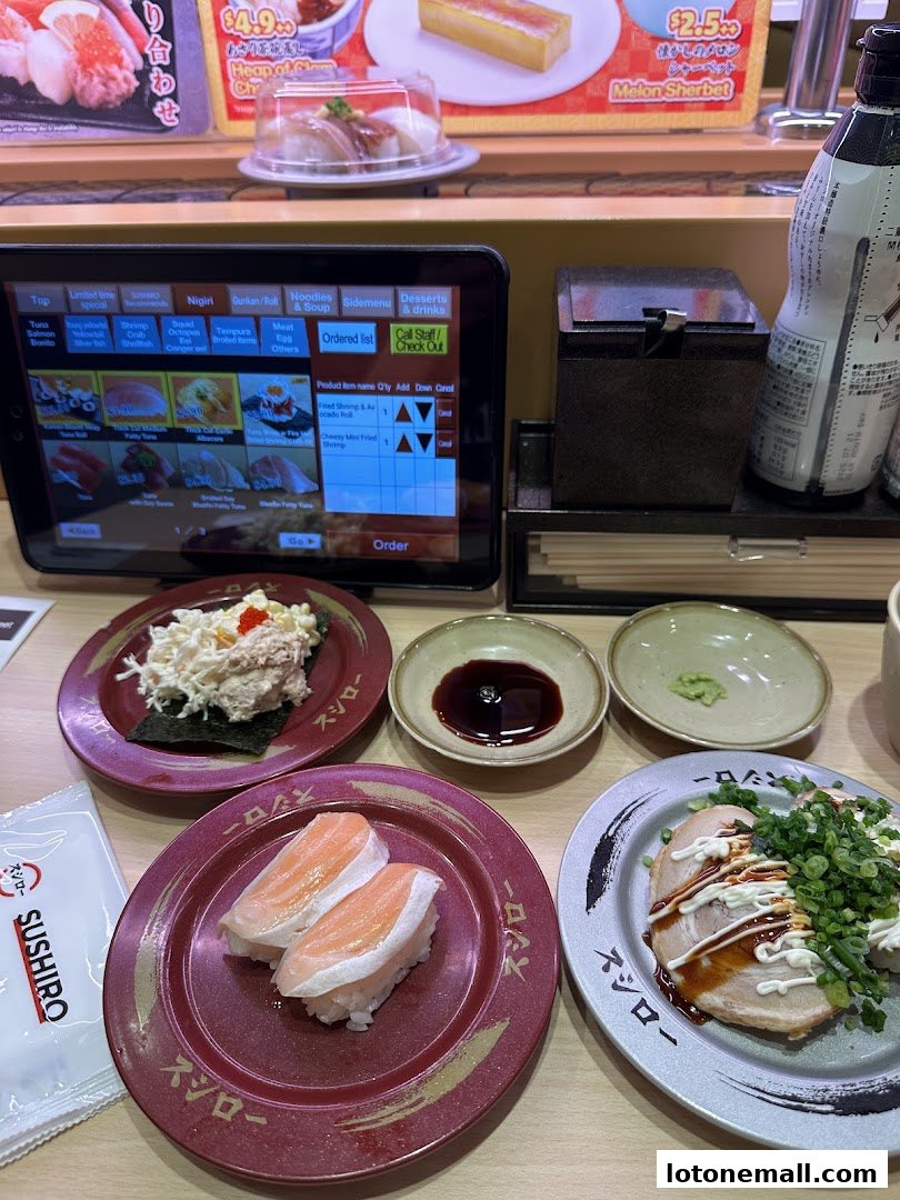A table at Sushiro with various sushi dishes, a tablet ordering system, and condiments.