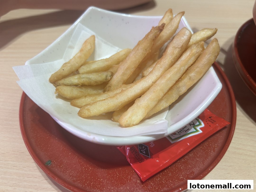 A close-up shot of a bowl of golden french fries served with a packet of ketchup.