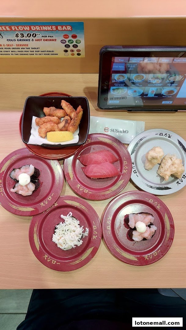 A table at Sushiro Lot One with various sushi plates, fried items, and a tablet menu.