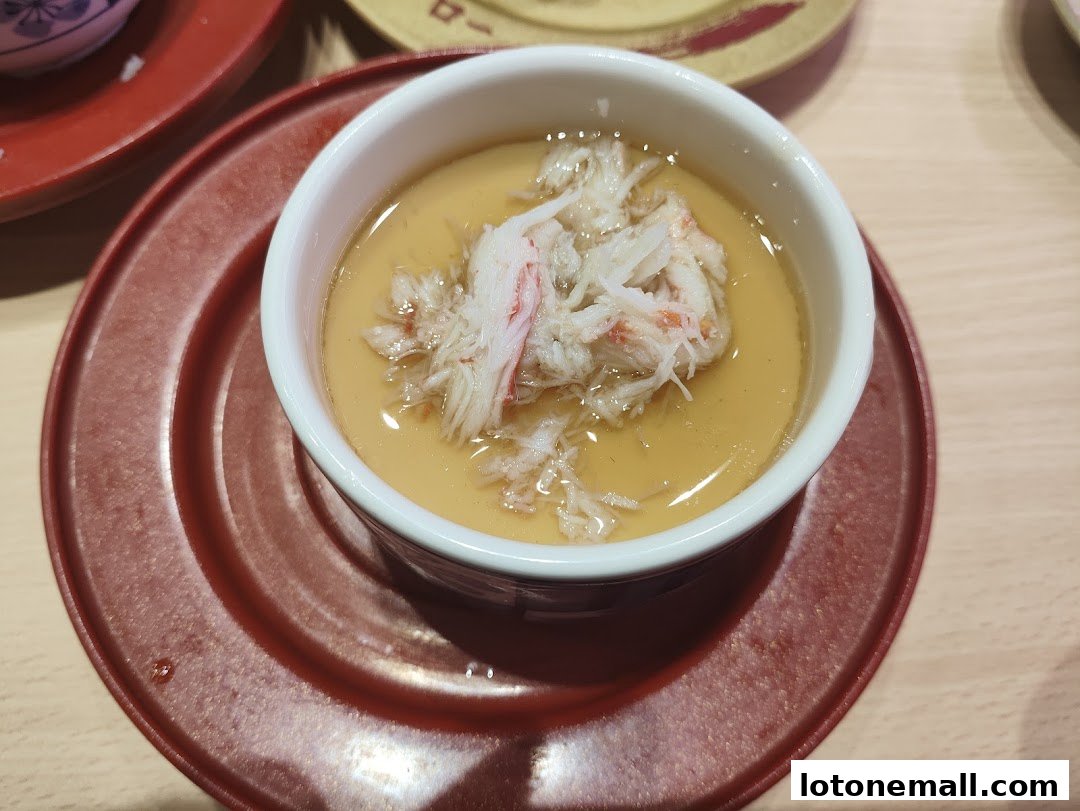 A close-up of a steaming bowl of chawanmushi topped with shredded crab meat.