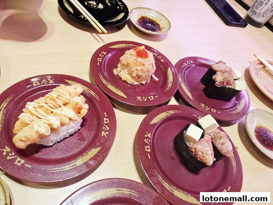 Plates of sushi with various toppings and sauces on a wooden table.