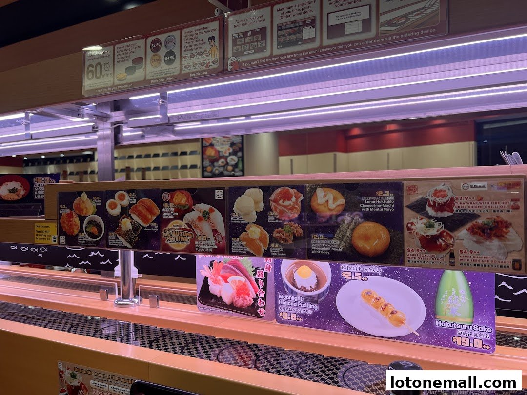A conveyor belt sushi restaurant display featuring various sushi dishes, desserts, and drinks.