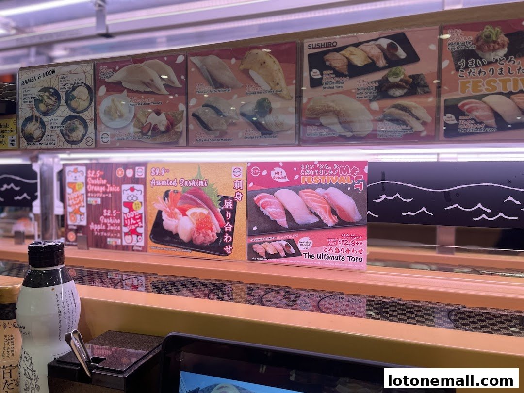 A conveyor belt sushi restaurant display featuring various sushi and sashimi dishes, drinks, and ramen.