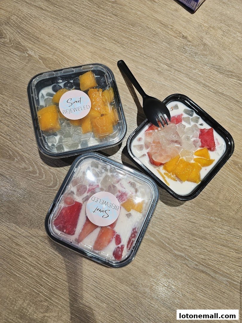 Three takeaway dessert bowls filled with fruits and creamy base, with a fork on one.