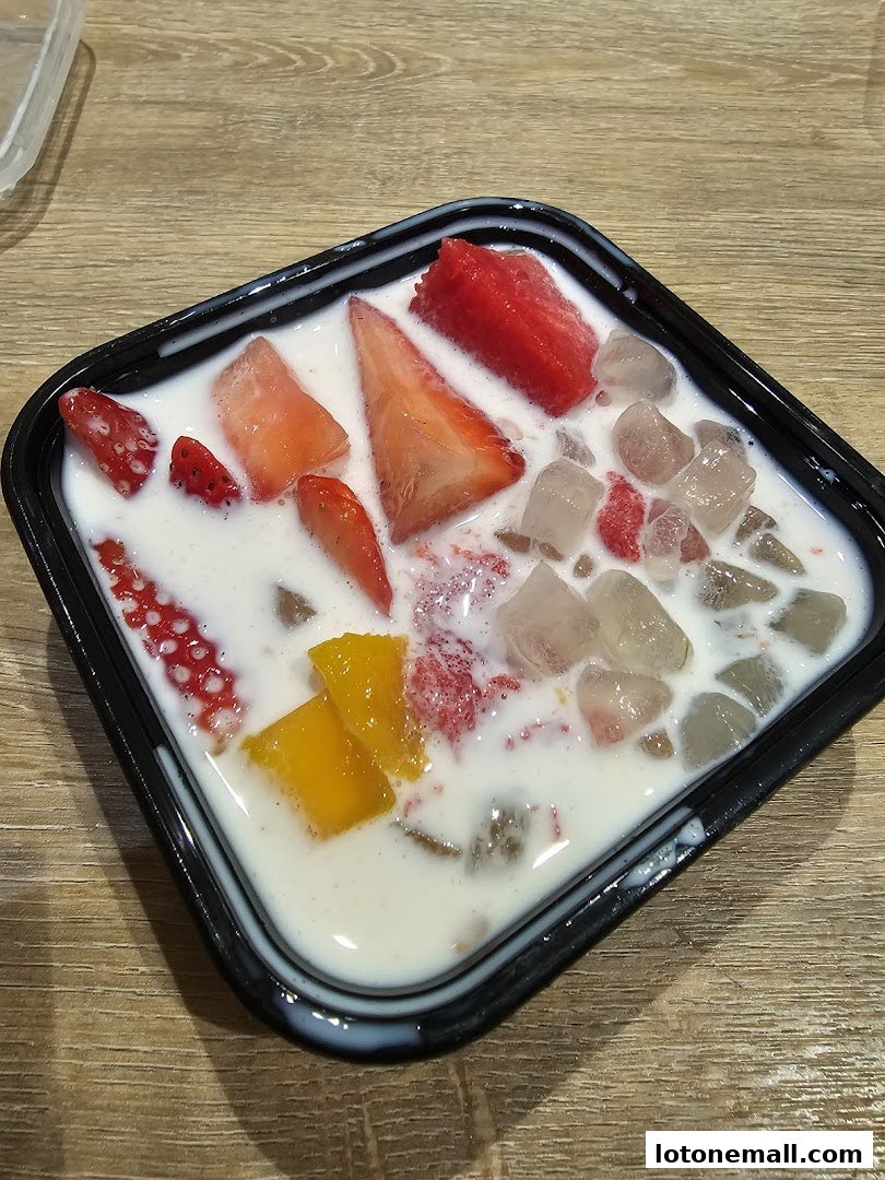 A refreshing dessert bowl filled with milk, strawberries, mango, and ice cubes.