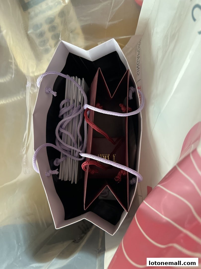 A white shopping bag filled with smaller gift bags containing jewelry.