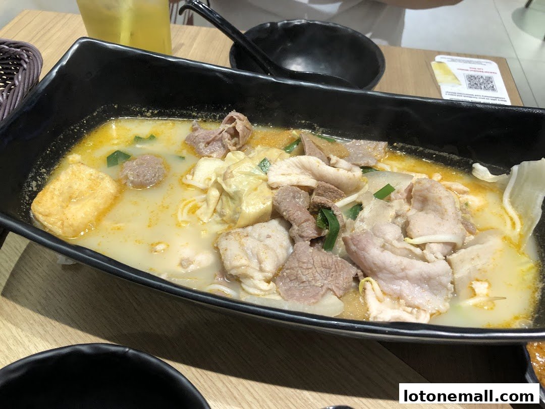 A steaming bowl of mixed ingredients in a flavorful broth with noodles.