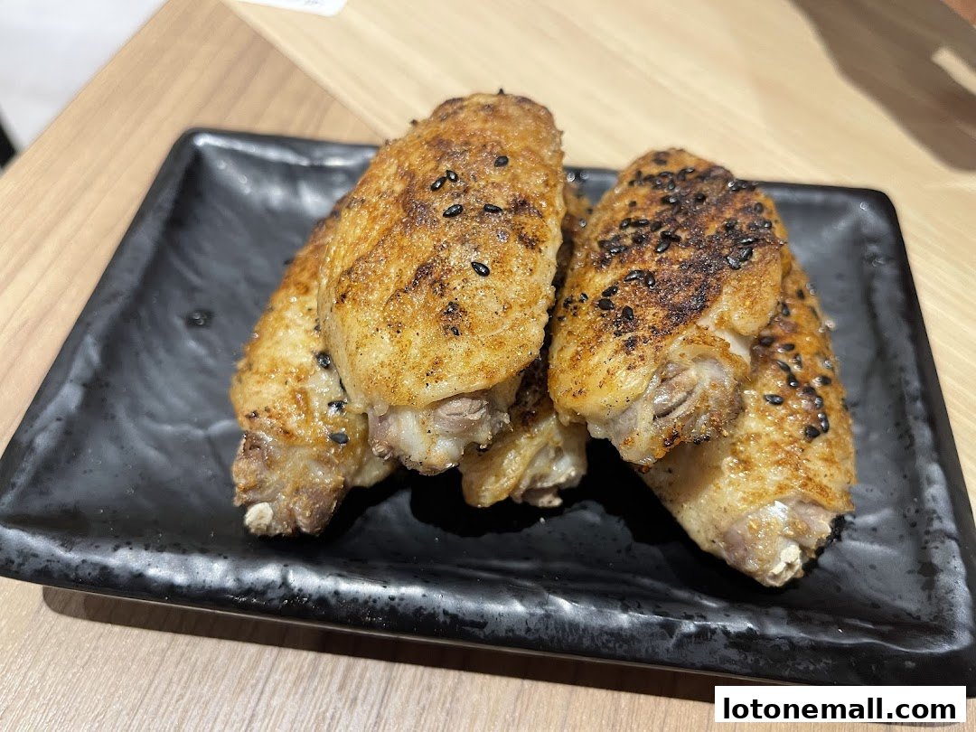 Close-up of crispy, golden-brown chicken wings seasoned with black sesame seeds.