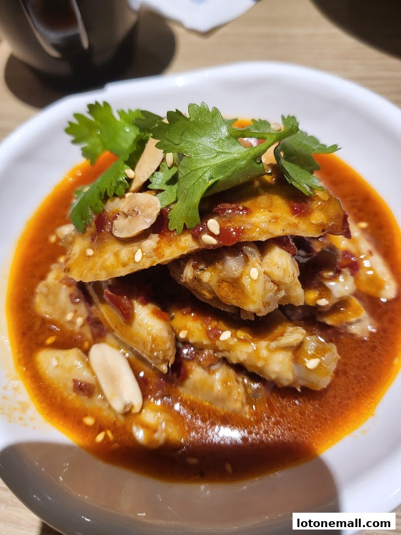 A close-up of a delicious dish with chicken wings in spicy sauce, garnished with cilantro and peanuts.