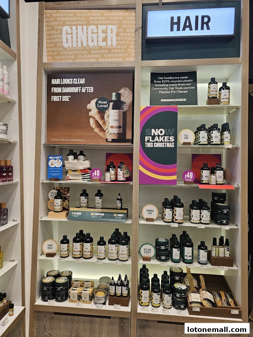 A display of The Body Shop hair care products, featuring ginger-scented items and promotional signage.