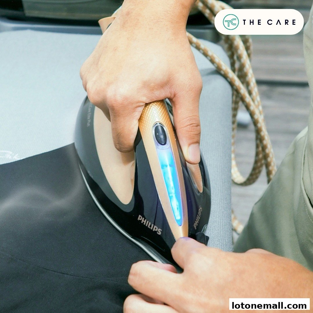 A person is ironing a black garment with a Philips iron, showing the brand logo.