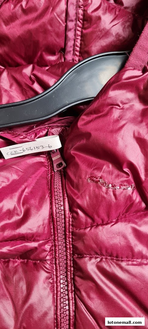 Close-up of a shiny burgundy puffer jacket with a zipper and a tag.