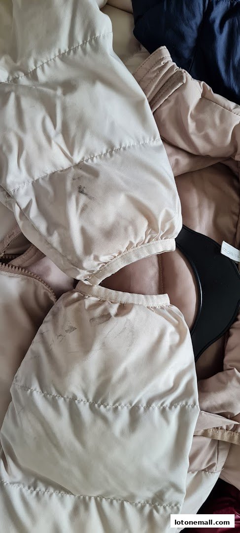 Close-up of stained light-colored puffer jacket sleeves and a black hanger.