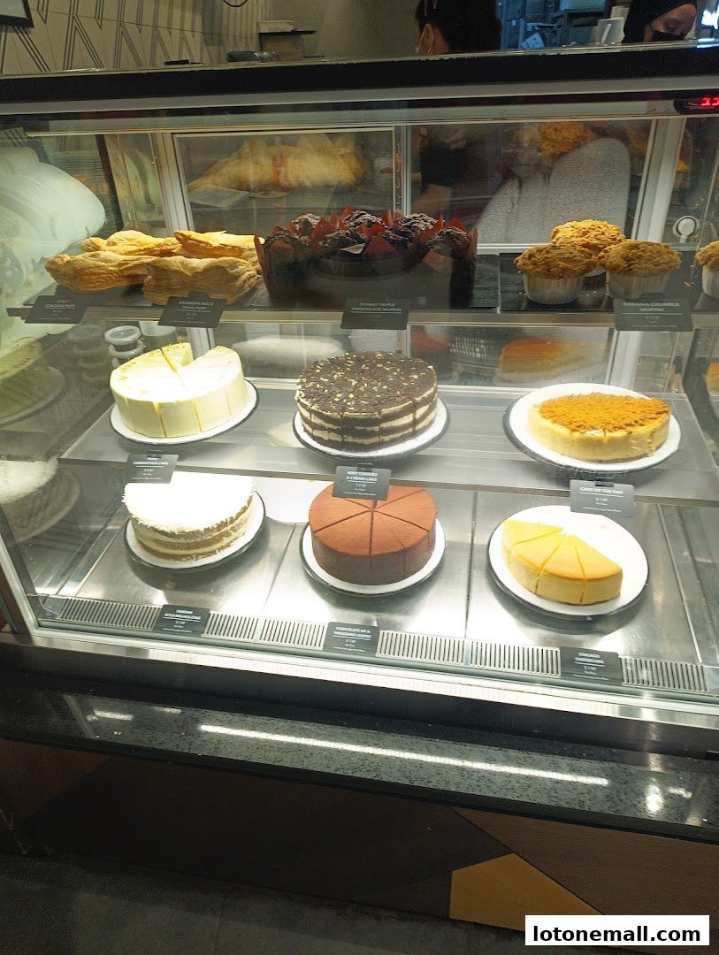 A display case filled with various cakes, pastries, and muffins at The Coffee Bean & Tea Leaf.