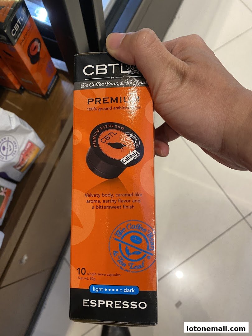 A hand holds a box of CBTL Premium Espresso single-serve coffee capsules.