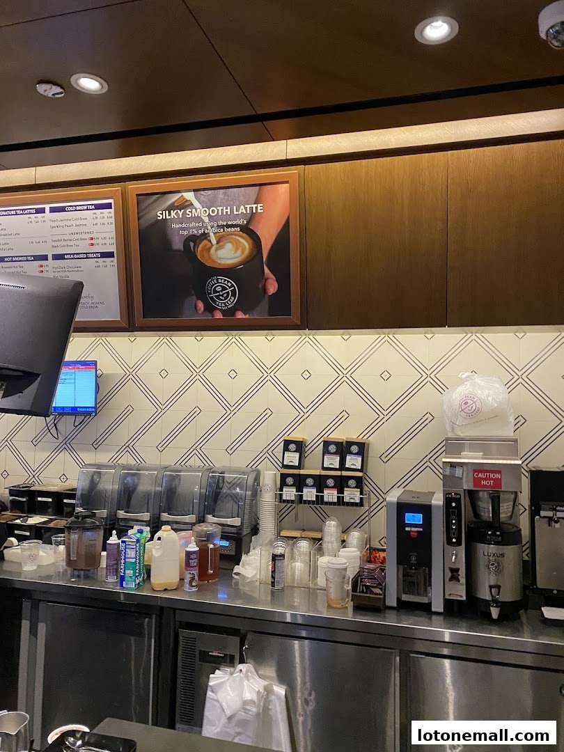 A coffee shop counter with brewing equipment, cups, and a menu board advertising lattes.