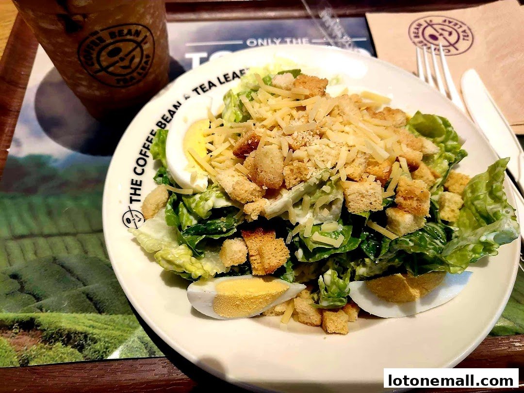 A close-up of a Caesar salad with a drink from The Coffee Bean & Tea Leaf.