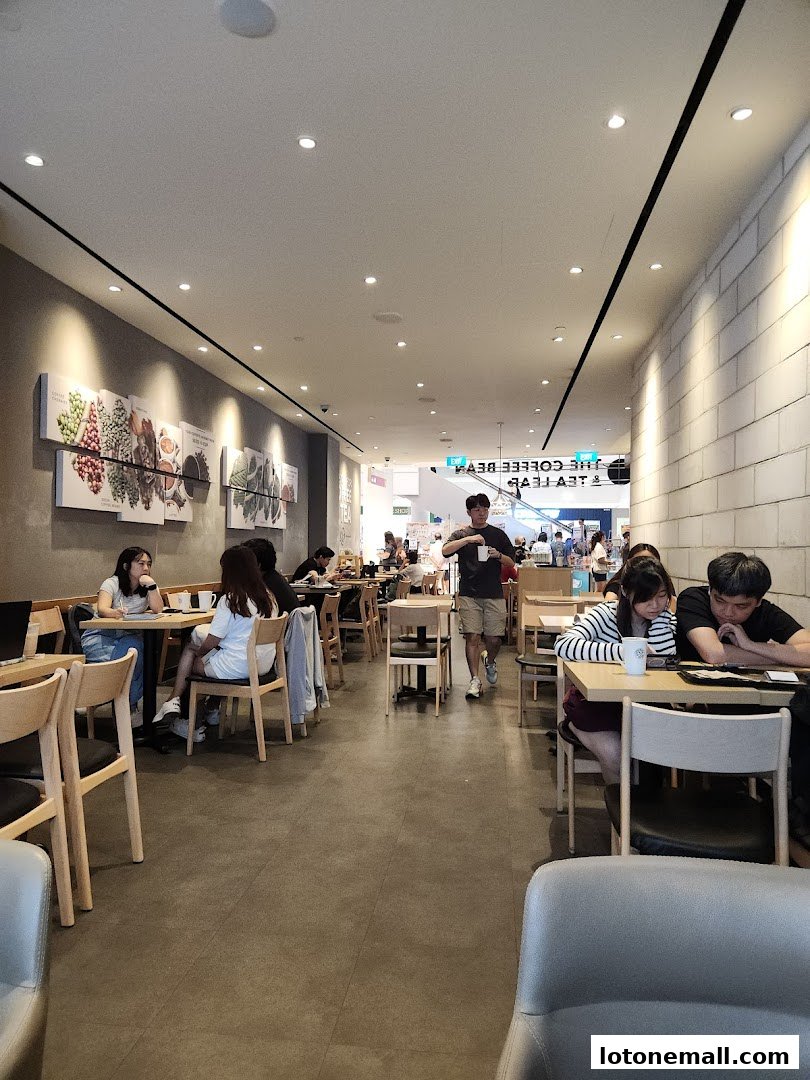 Interior of The Coffee Bean & Tea Leaf with customers seated at tables and a person walking.