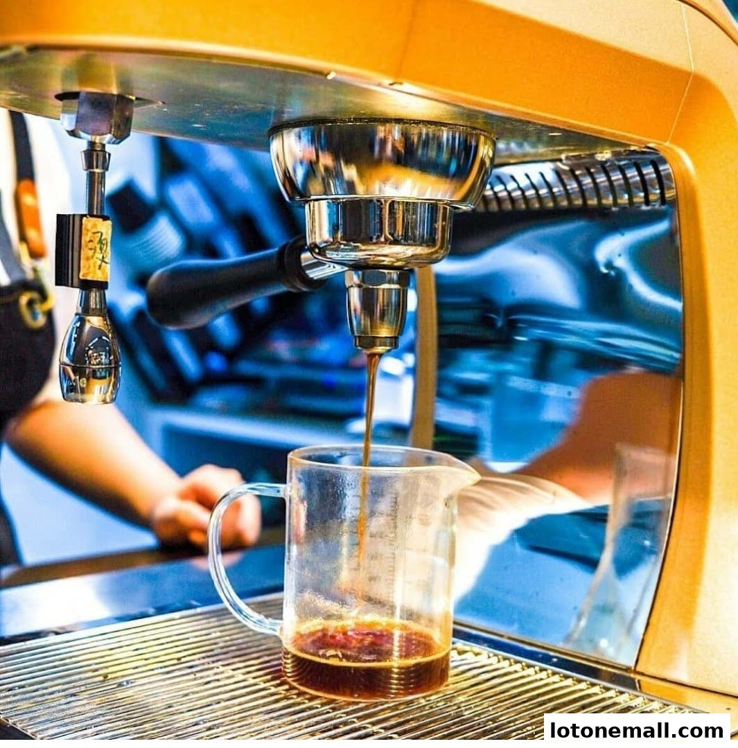 A barista prepares coffee using an espresso machine, pouring into a glass pitcher.