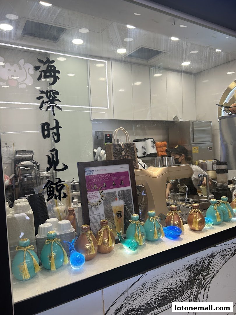 A display of decorative bottles and whale figures in front of a bubble tea shop counter.