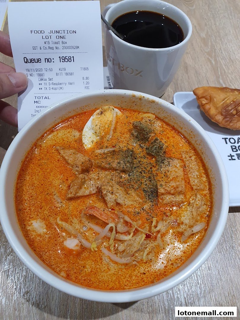 A bowl of Laksa with a cup of coffee and a pastry from Toast Box.