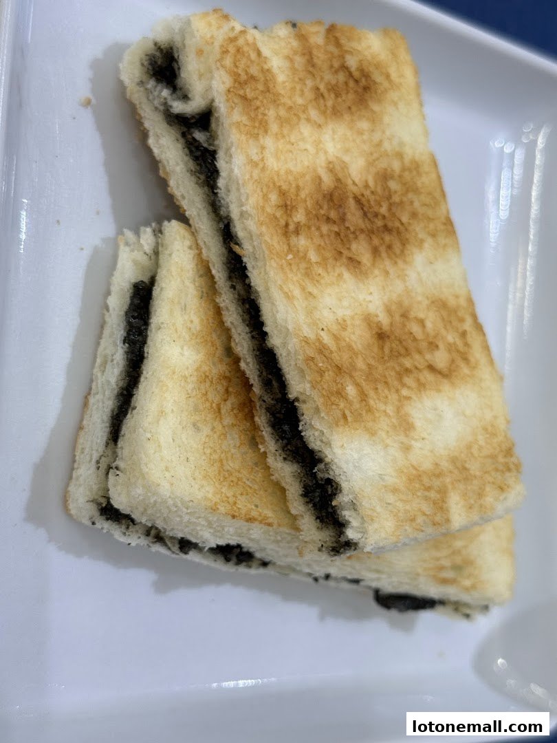 Close-up of toasted bread slices filled with a dark spread, served on a white plate.