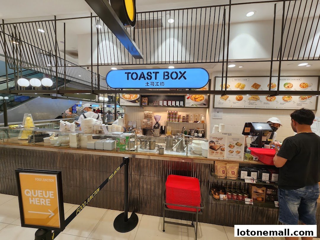 A Toast Box food stall with a queue sign and customers ordering at the counter.