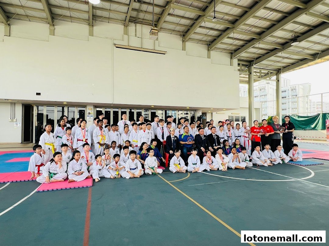A large group of children and adults in martial arts uniforms pose for a photo after an event.