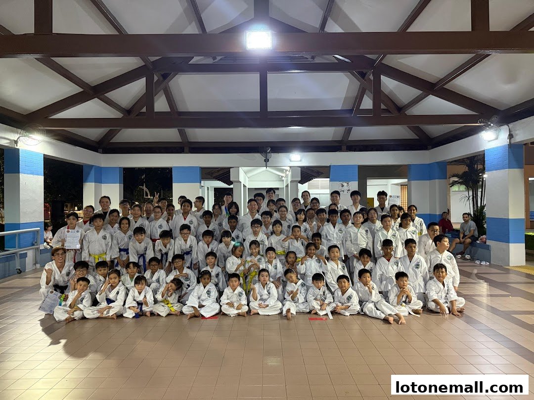 A large group of people, mostly children, in martial arts uniforms pose for a photo.