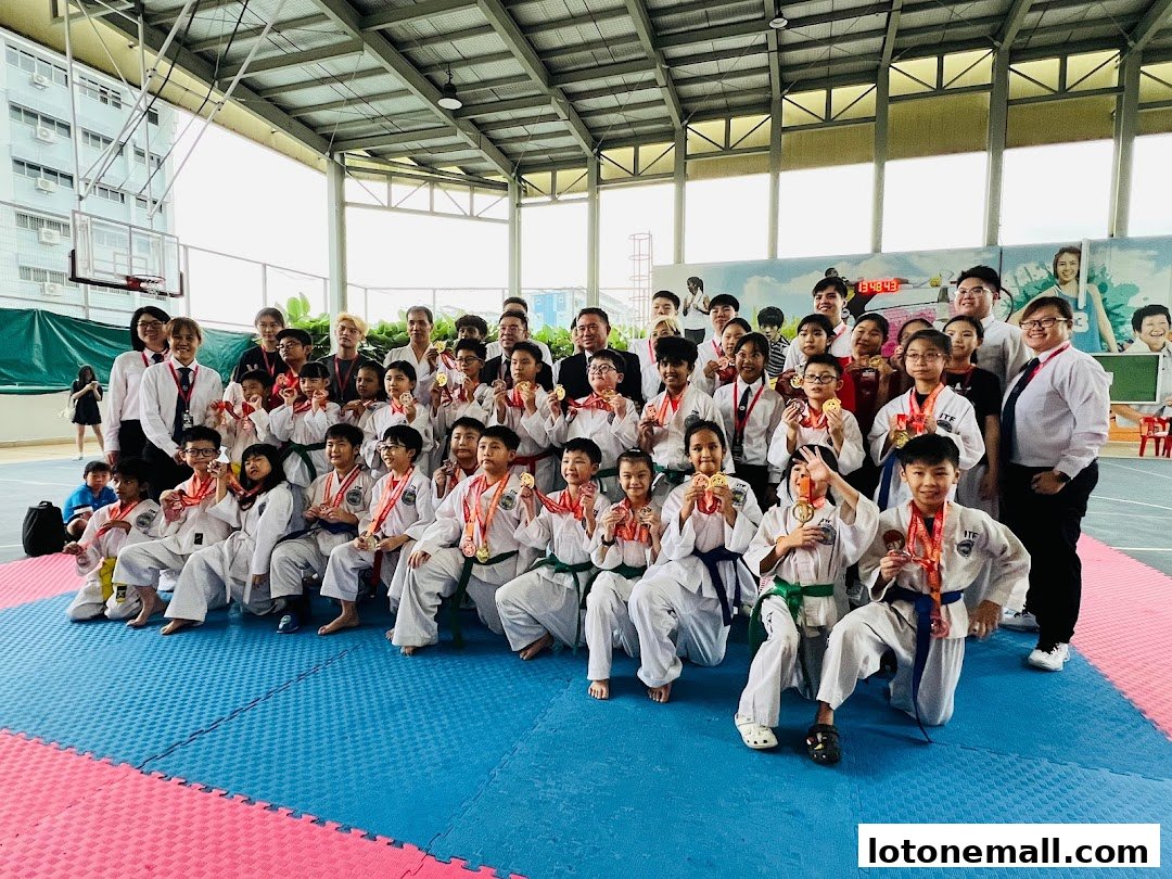 A group of children and adults in martial arts uniforms pose for a photo with medals.