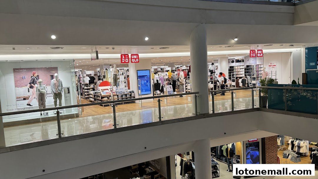 Interior view of a brightly lit Uniqlo store with mannequins displaying clothing and shelves stocked with apparel.