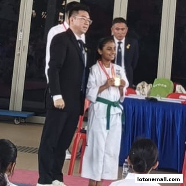 A young girl in a karate uniform receives a medal from officials.