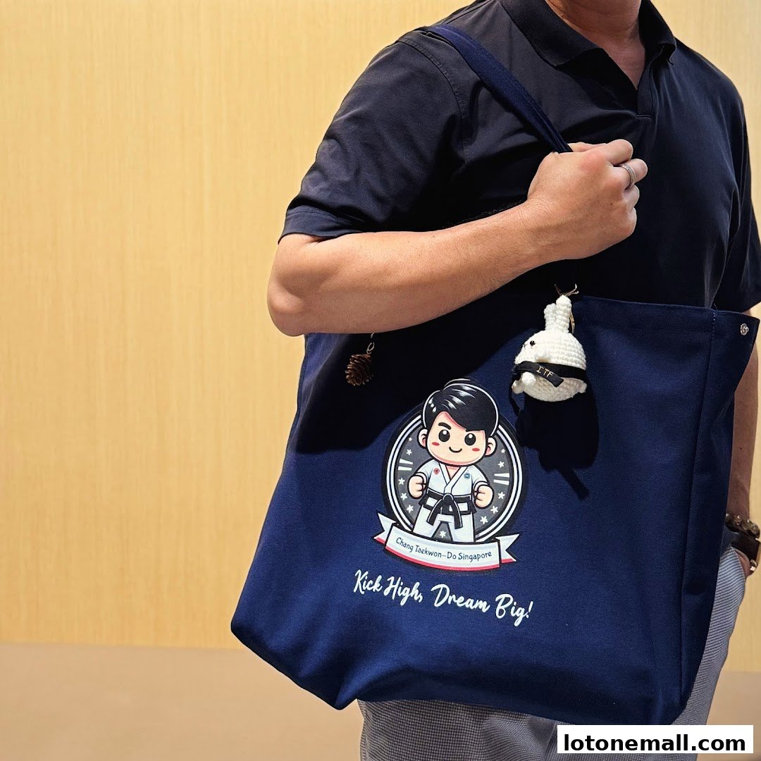 A person carries a navy blue tote bag with a cartoon martial artist and motivational text.