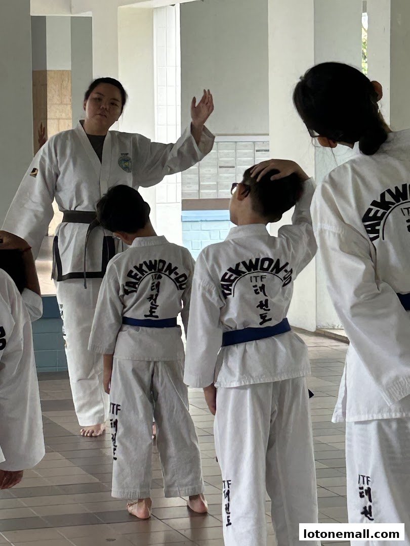 A Taekwondo instructor demonstrates a move to students in a training session.