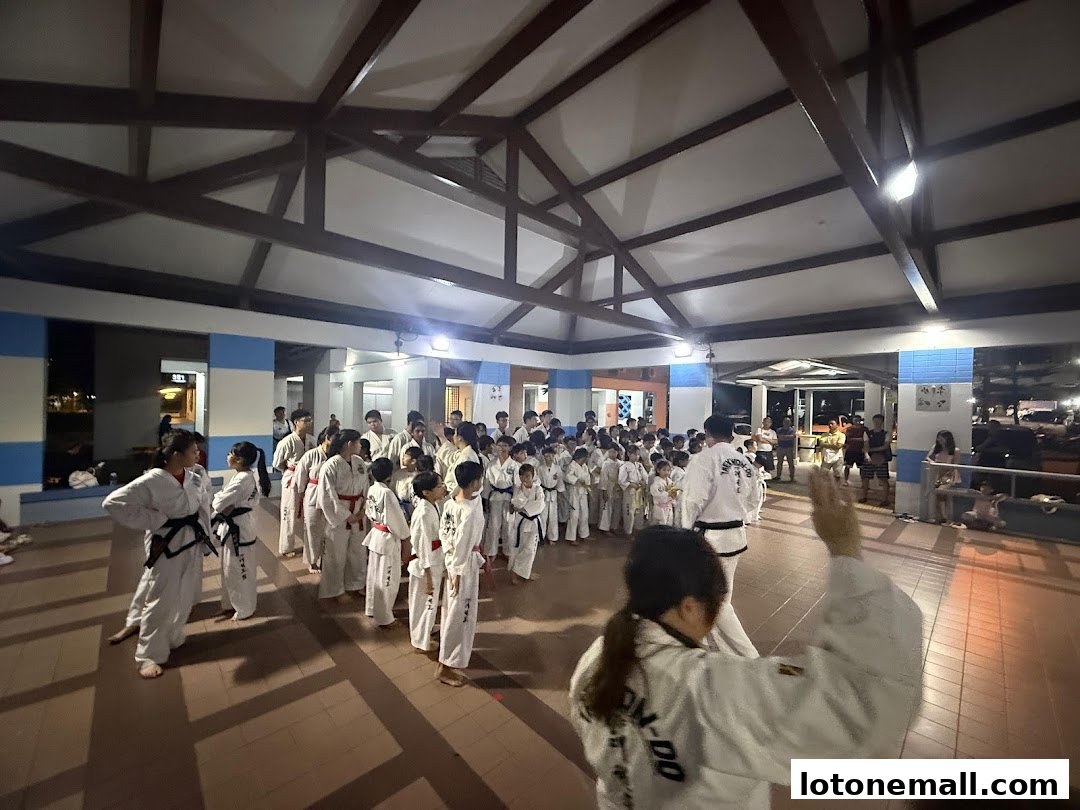 A large group of people in taekwondo uniforms gathered indoors.