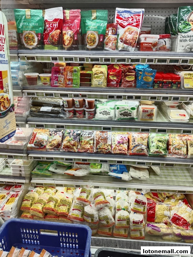 A refrigerated display case filled with various packaged food items, including noodles, kimchi, and other Asian delicacies.