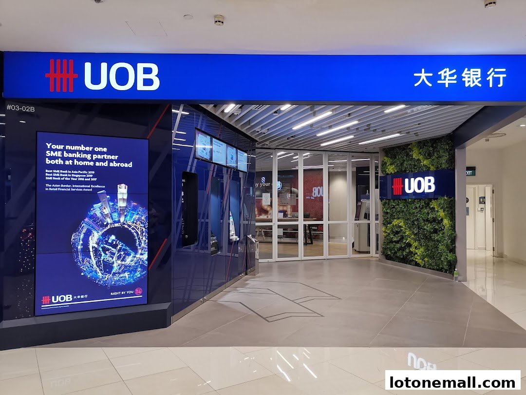 The entrance to a UOB bank branch with a digital display and a green wall.