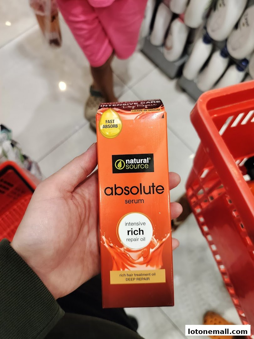A hand holds a box of 'Absolute Serum' hair treatment oil in a store.